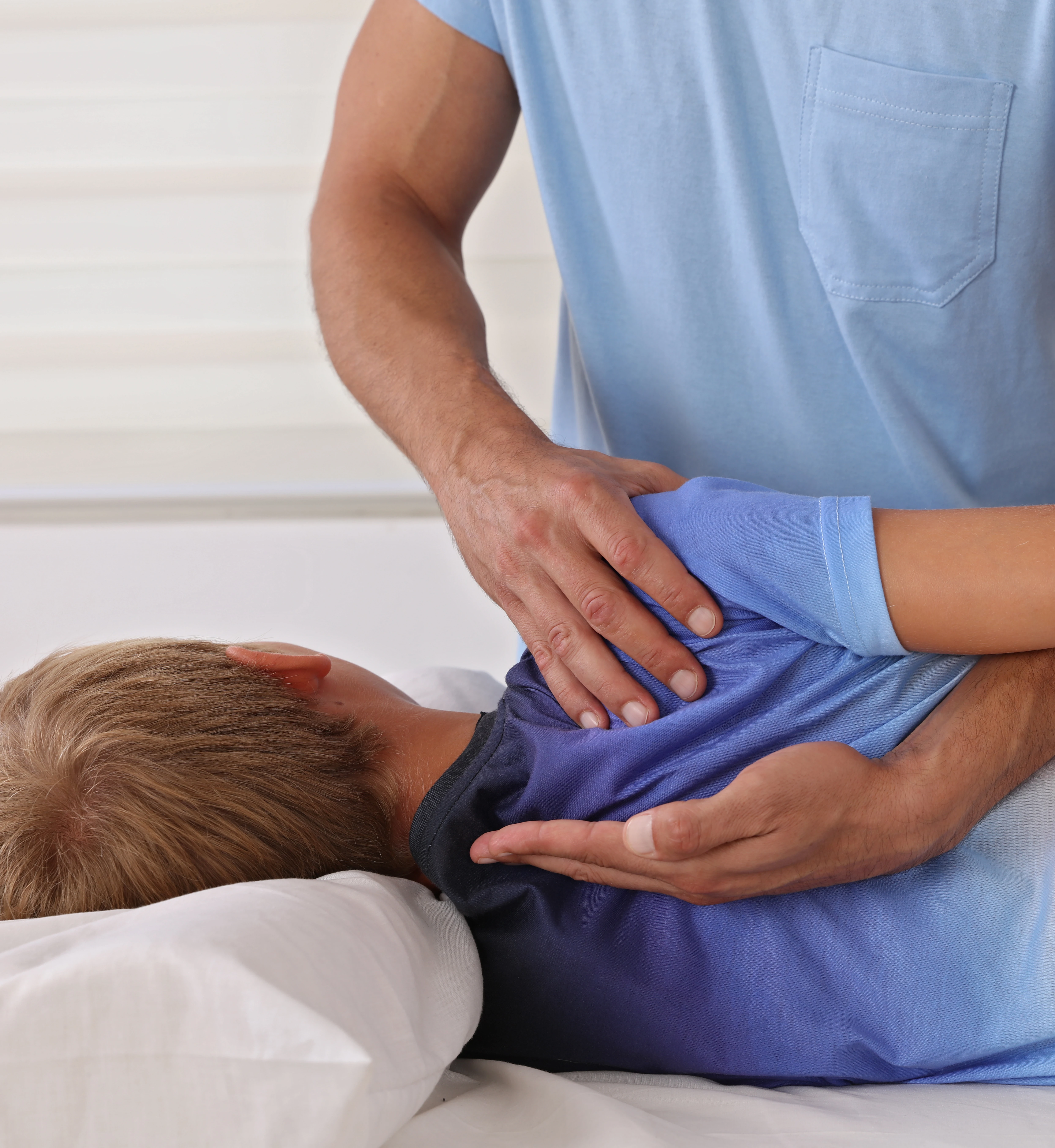 Chiropractor gently adjusting child patient spine
