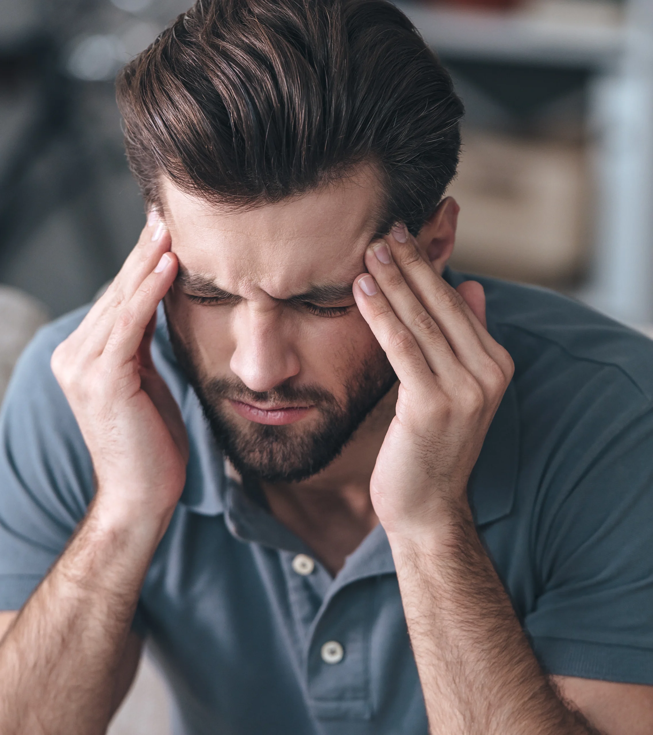 Patient pressing hands to temples experiencing a chronic headache